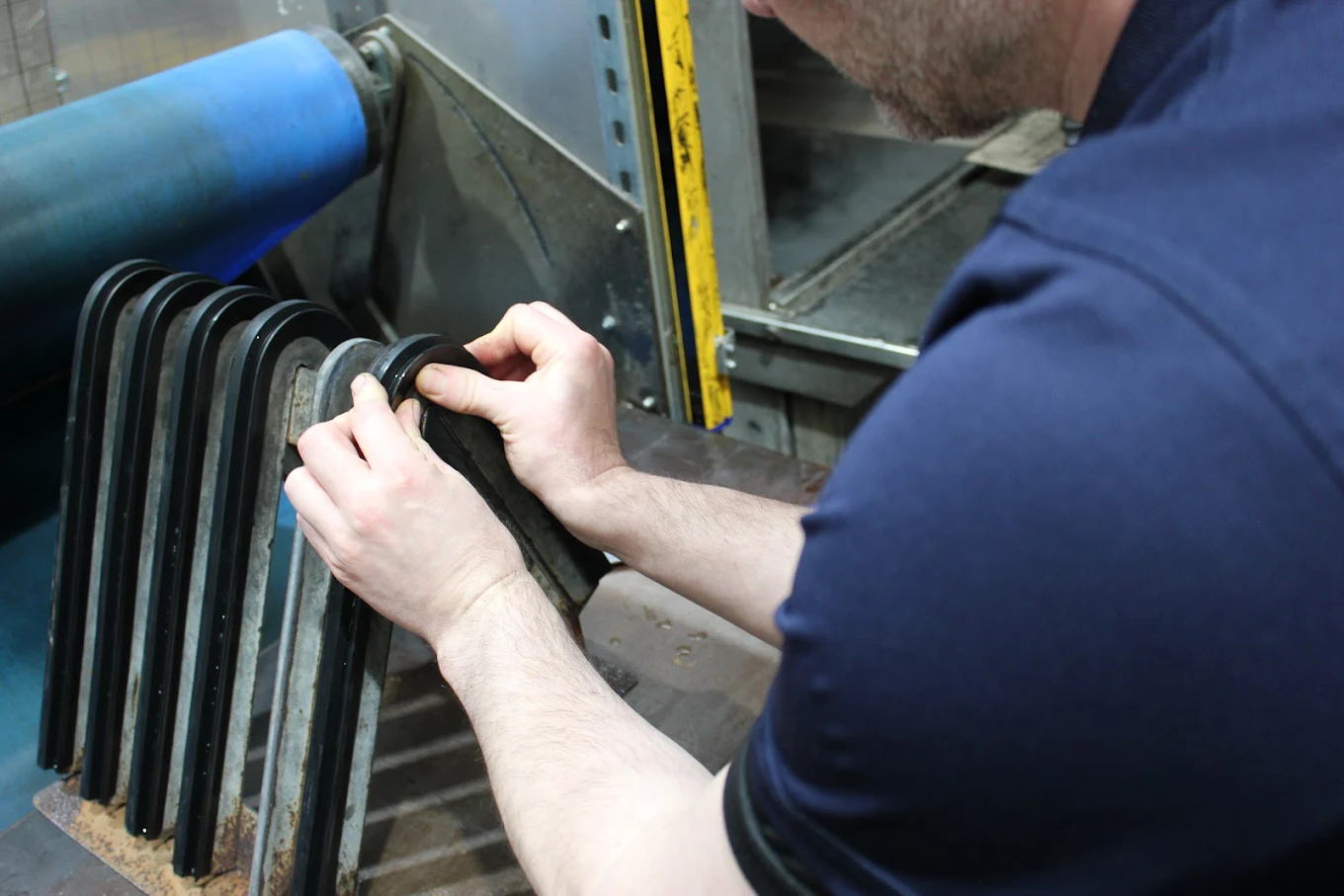 A manufacturing technician demonstrates the forming process, using his thumbs to shape rubber around a metal frame into a point